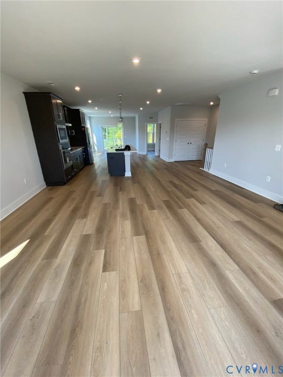 2701 St Elias Drive, #B, Richmond, VA 23294 Spacious open-concept living area featuring wood-finish flooring, recessed lighting, and a kitchen island with dark cabinetry