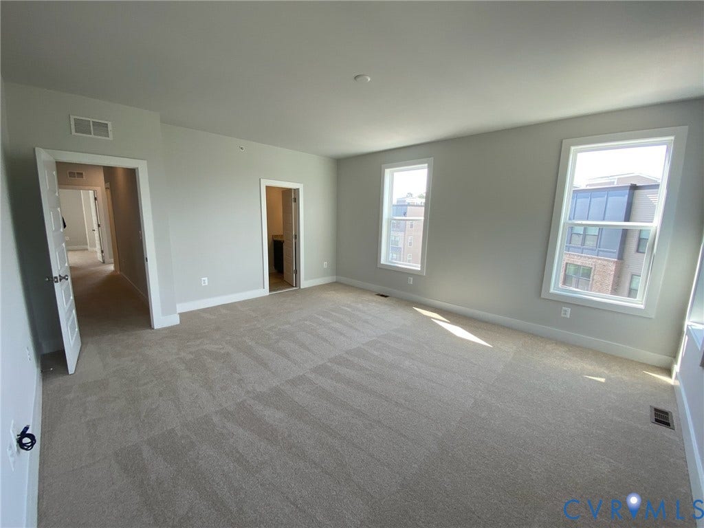 2701 St Elias Drive, #B, Richmond, VA 23294 Expansive room featuring neutral-toned carpeting, multiple windows with white trim, and light gray wall finishes