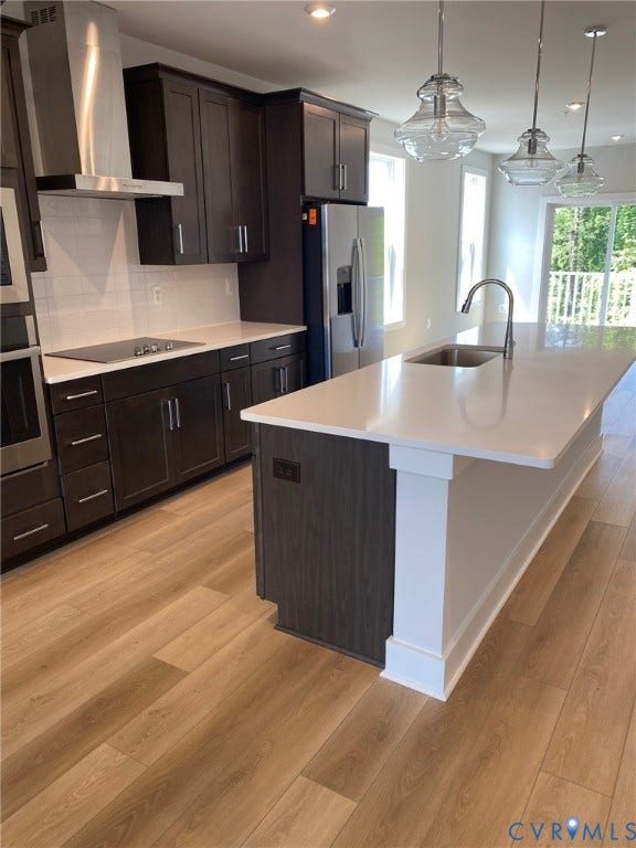 2701 St Elias Drive, #B, Richmond, VA 23294 Modern kitchen featuring dark wood cabinetry, stainless steel appliances, a center island with sink, crisp white countertops, and wood-finish flooring