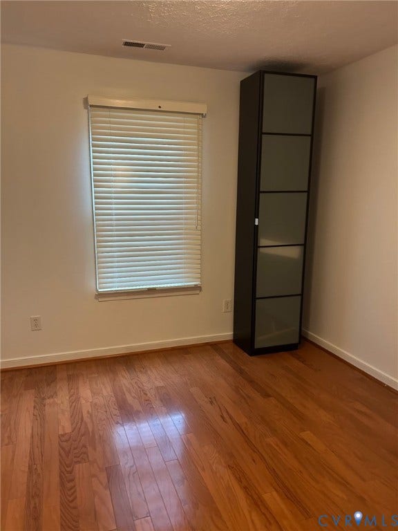 Hardwood-style flooring in a warm finish, with a built-in wall cabinet and window blinds