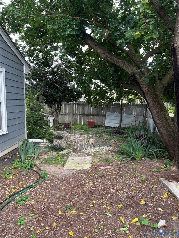 Backyard area featuring a mature tree, privacy fencing, and sidings