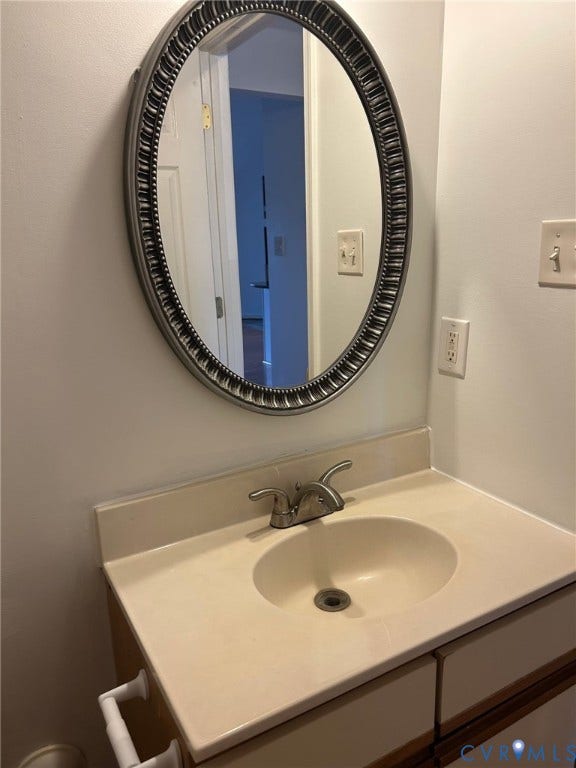 Vanity with an integrated sink and base cabinetry, complemented by an oval wall-mounted mirror