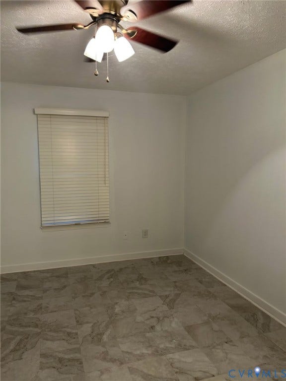 Neutral wall paint throughout, wood-finish ceiling fan with integrated lighting, window with horizontal blinds, and patterned tile flooring