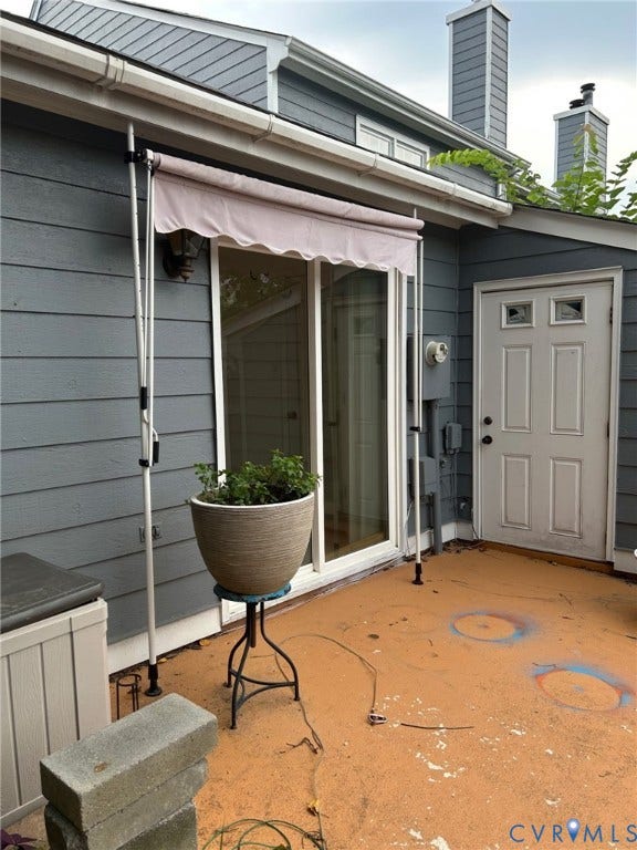 Exterior siding in a gray finish with white trim, featuring a sliding glass door with an awning