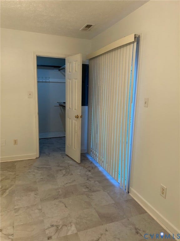 Light-toned walls, tile-finish flooring, white paneled interior door, and vertical blinds