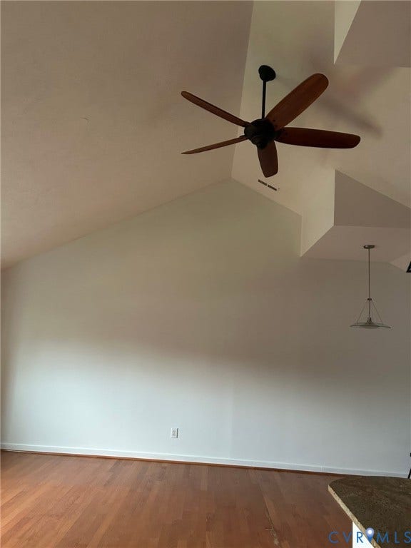 Angled white vaulted ceiling with a dark-toned ceiling fan featuring wood-finish blades