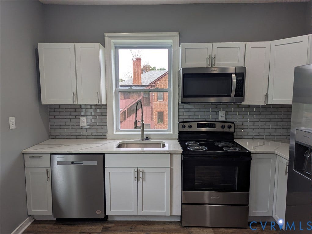 4202 Chamberlayne Avenue, Richmond, VA 23227 White cabinetry, stainless steel appliances, subway tile backsplash, light-toned countertops, and wood-finish flooring