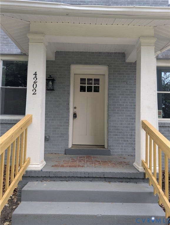 4202 Chamberlayne Avenue, Richmond, VA 23227 Brick facade with a covered porch, featuring a paneled entry door with windowpanes, and an exterior wall lantern
