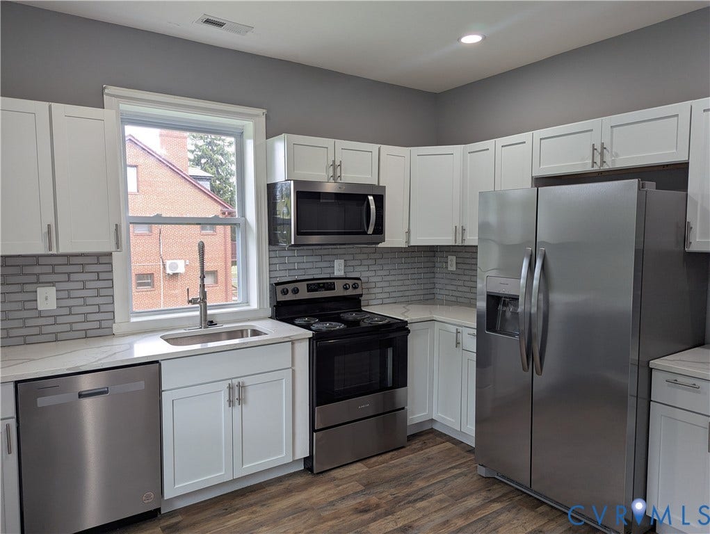 4202 Chamberlayne Avenue, Richmond, VA 23227 Contemporary kitchen featuring white cabinetry, stainless steel appliances, a subway tile backsplash, and wood-finish flooring