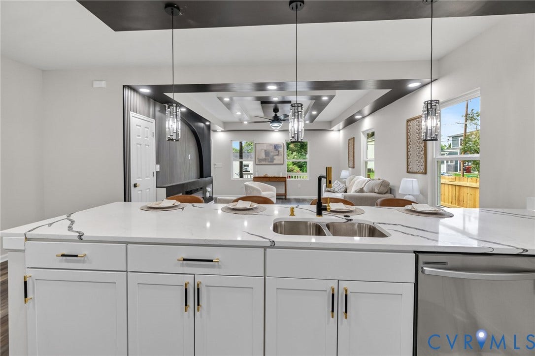 1146 Willcox Street, Petersburg, VA 23803 Kitchen island featuring a dual-basin stainless steel sink with a matte black faucet, white cabinetry with black and gold hardware, and a white countertop with grey veining