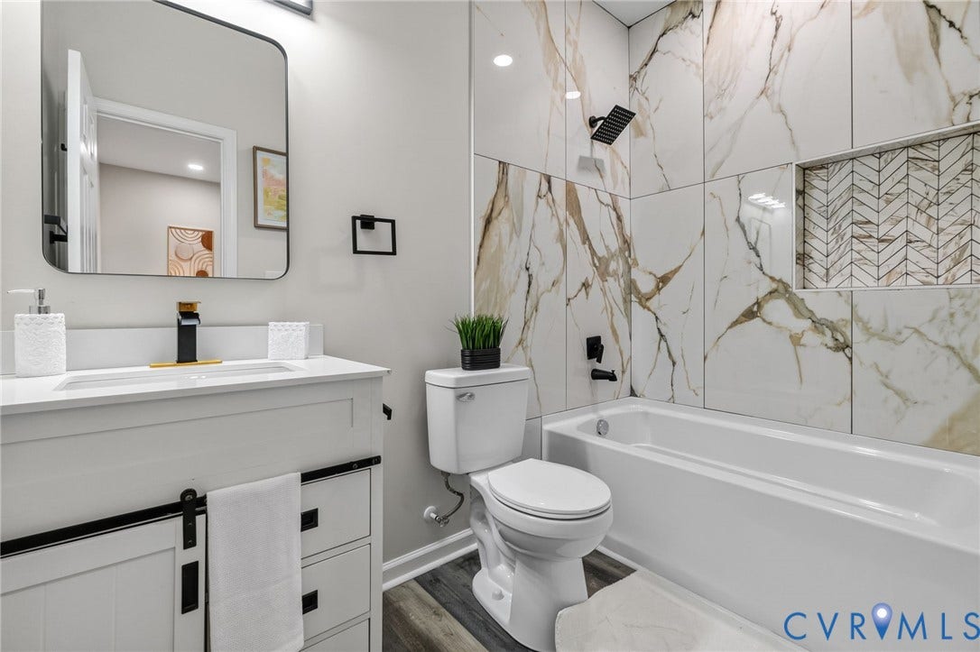 1146 Willcox Street, Petersburg, VA 23803 Bathroom featuring a white vanity with a black and gold faucet, a rectangular mirror, a toilet, and a bathtub with a shower