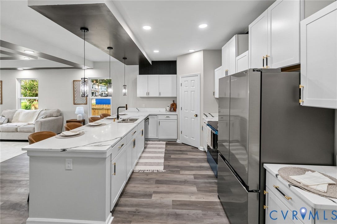 1146 Willcox Street, Petersburg, VA 23803 Spacious kitchen featuring an extended island with a light-toned countertop, ample white cabinetry with gold-tone hardware, stainless steel appliances, wood-finish flooring, and recessed ceiling lighting