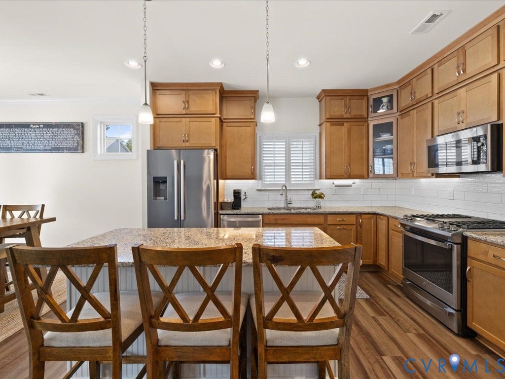 1801 Outrigger Drive, Meadowville Landing, Chesterfield, VA 23836 Kitchen featuring wood-finish cabinetry, stainless steel appliances, granite-style countertops, white subway tile backsplash, and a central island with pendant lighting