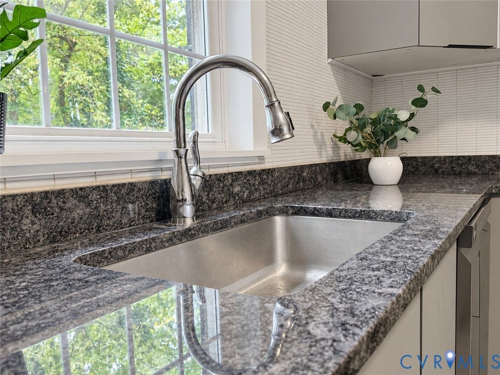 518 Central Terrace, Hopewell, VA 23860 Stainless steel undermount sink with a gooseneck faucet, set within a granite-finish countertop, complemented by a tiled backsplash and overhead cabinetry