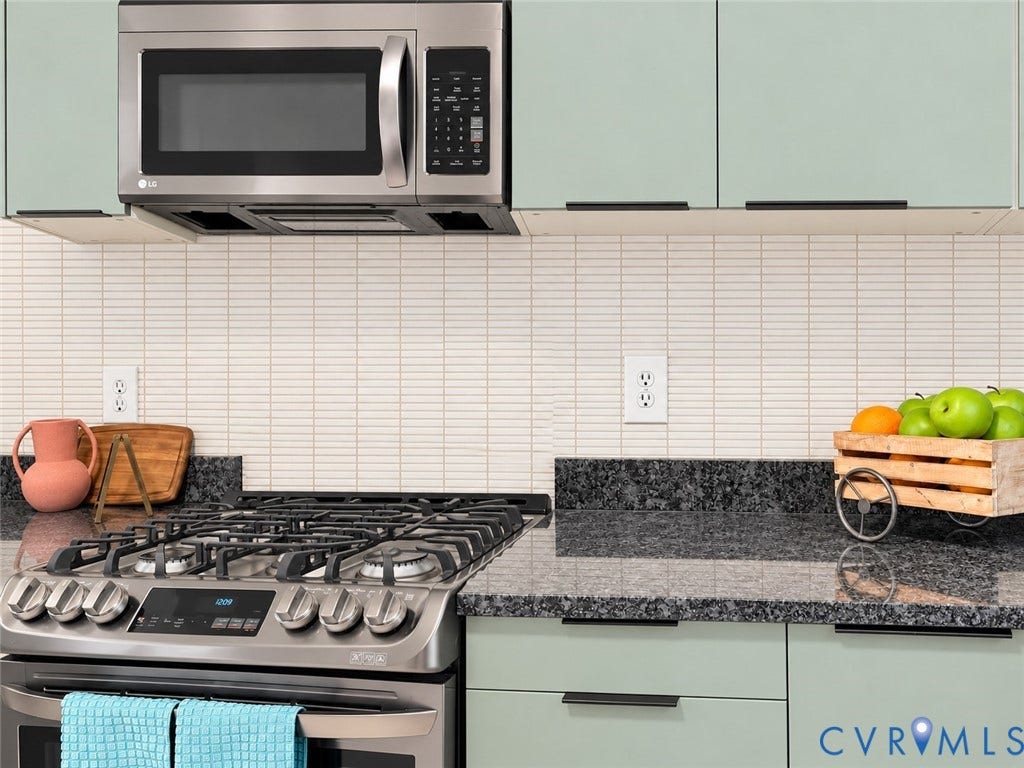 518 Central Terrace, Hopewell, VA 23860 Stainless steel microwave, light green cabinetry with black hardware, white horizontal tile backsplash, dark granite countertops, and a stainless steel gas range