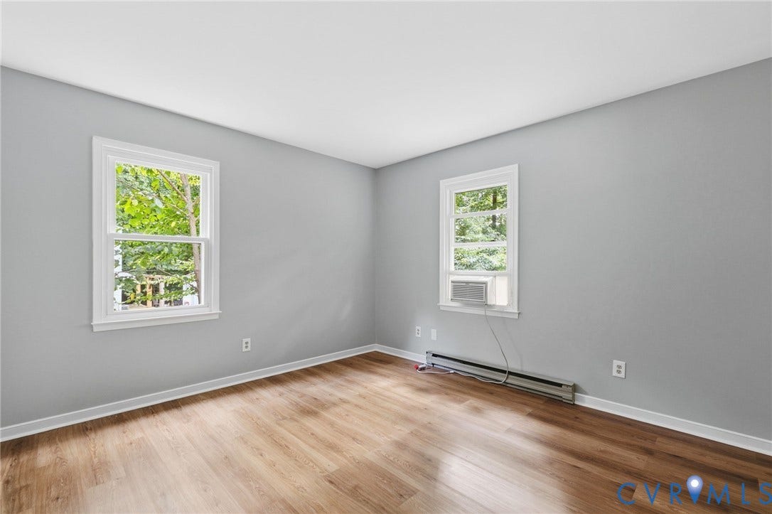 5571 Heatherhill Drive, Whale Rock, North Chesterfield, VA 23234 Wood-finish flooring, light gray wall paint, two windows with white trim, and a window-mounted air conditioning unit