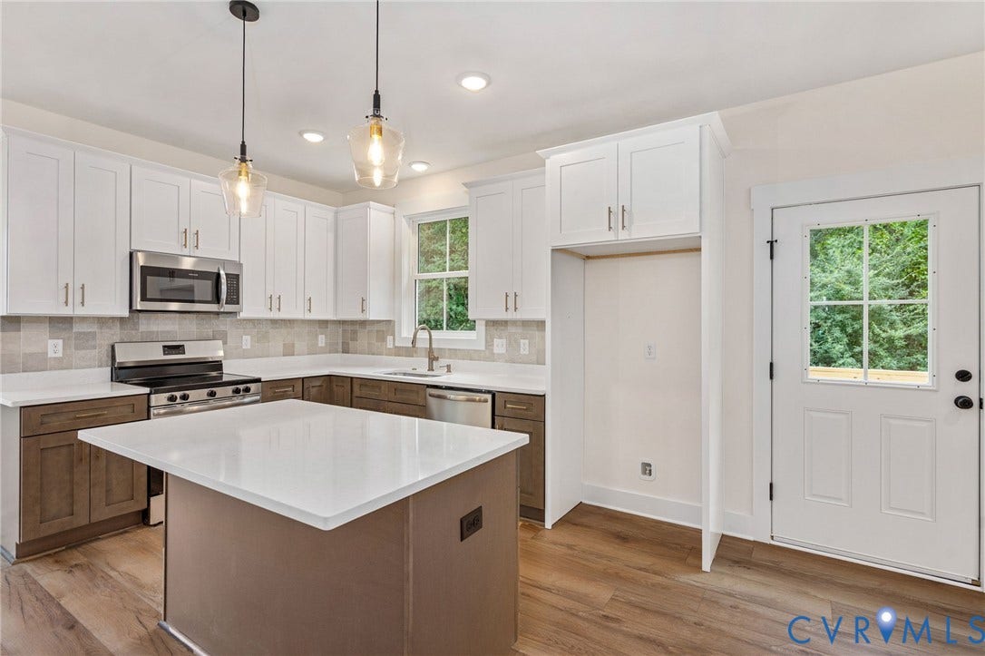 7605 Oster Drive, Chamberlayne Farms Area, Henrico, VA 23227 Kitchen featuring white shaker cabinetry, stainless steel appliances, a center island with a solid surface countertop, wood-finish flooring, and a glass-paned door