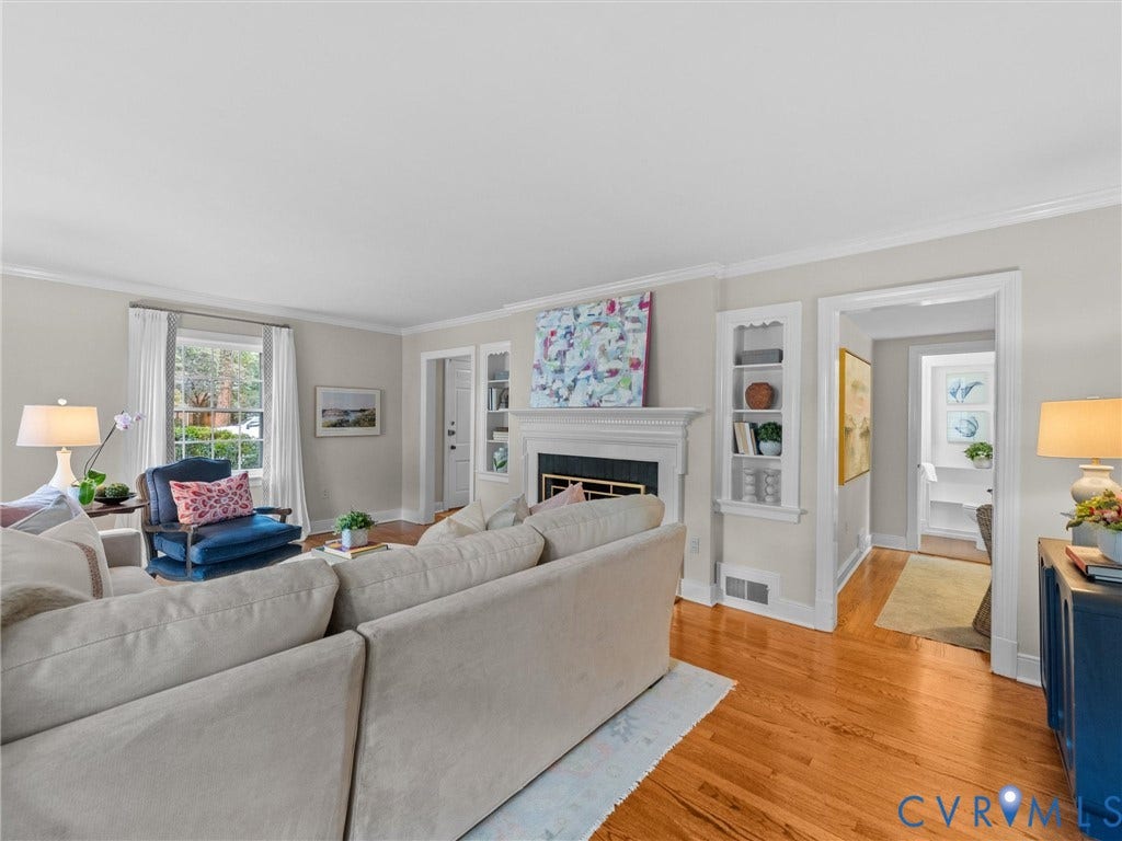 1113 E Durwood Crescent, Tuckahoe Area, Henrico, VA 23229 Hardwood flooring throughout, a white-mantled fireplace, built-in shelving, white trim, and a window with exterior views