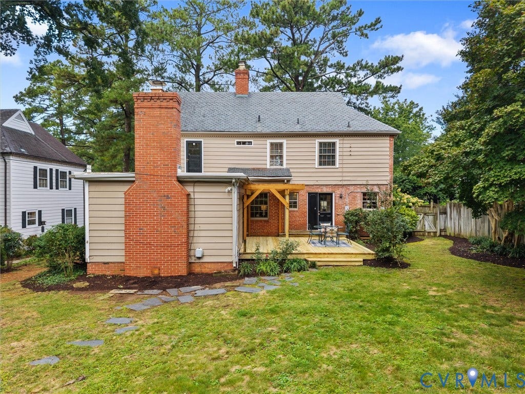 1113 E Durwood Crescent, Tuckahoe Area, Henrico, VA 23229 Expansive backyard featuring a manicured lawn, stone pathway, brick chimney, wooden deck, and mature trees