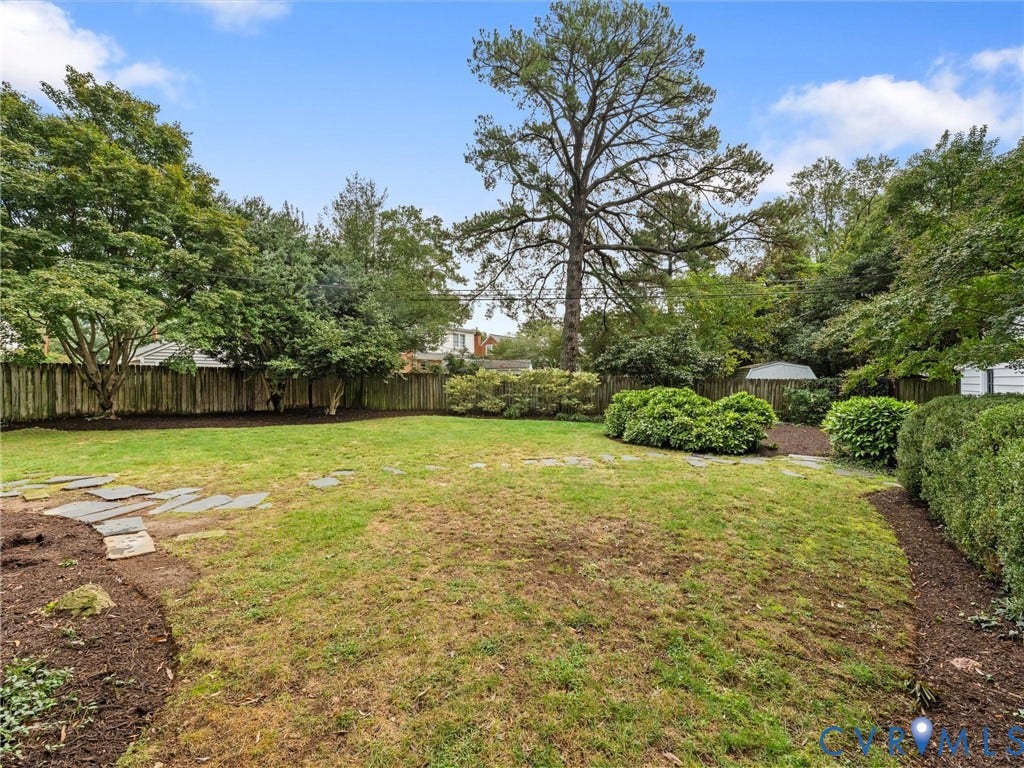 1113 E Durwood Crescent, Tuckahoe Area, Henrico, VA 23229 Expansive backyard featuring a wood fence, mature trees, landscaped beds, and flagstone pathways