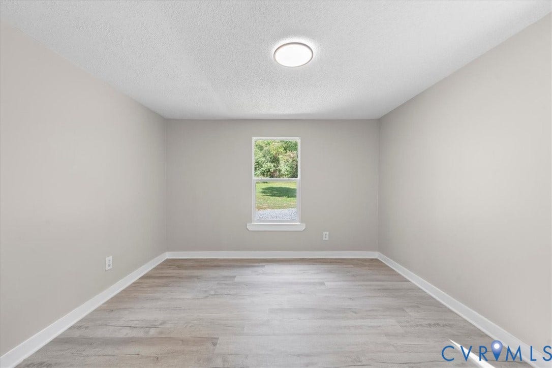 115 Mount Airy Lane, Cumberland, VA 23040 Bright, light-filled bedroom showcasing wood-finish flooring, recessed ceiling lighting, and a large window framing natural outdoor scenery