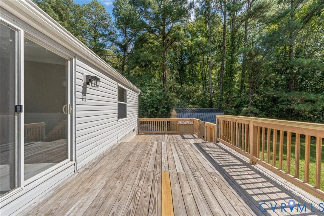 115 Mount Airy Lane, Cumberland, VA 23040 Expansive wood deck with natural wood railing, featuring a sliding glass door and exterior wall sconce