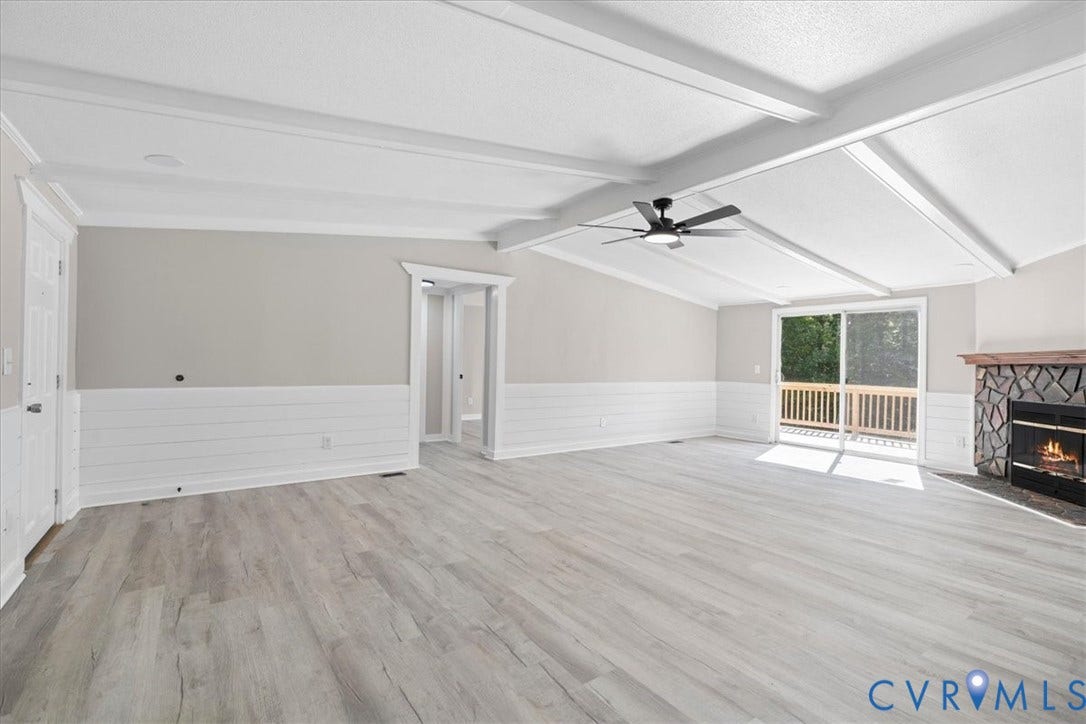 115 Mount Airy Lane, Cumberland, VA 23040 Vaulted ceiling with exposed beams, wood-finish flooring, stone fireplace, shiplap accent wall, and sliding glass door to a private deck