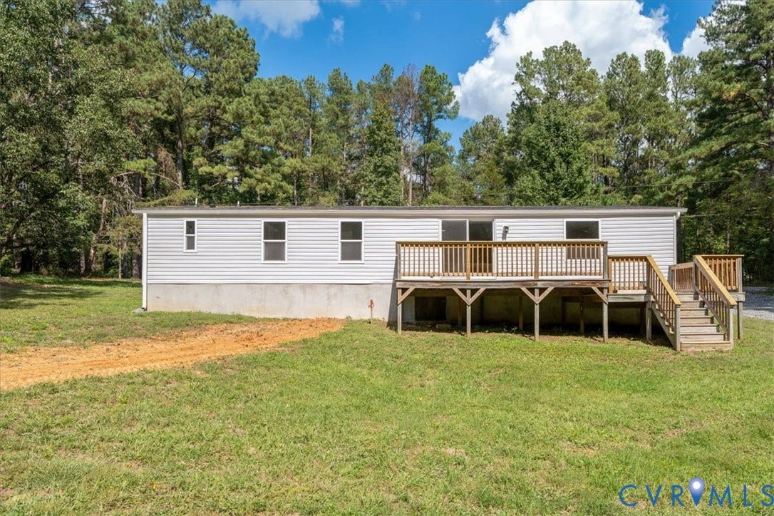 115 Mount Airy Lane, Cumberland, VA 23040 Rear exterior featuring a large wood deck with stairs, white siding, and surrounding mature trees