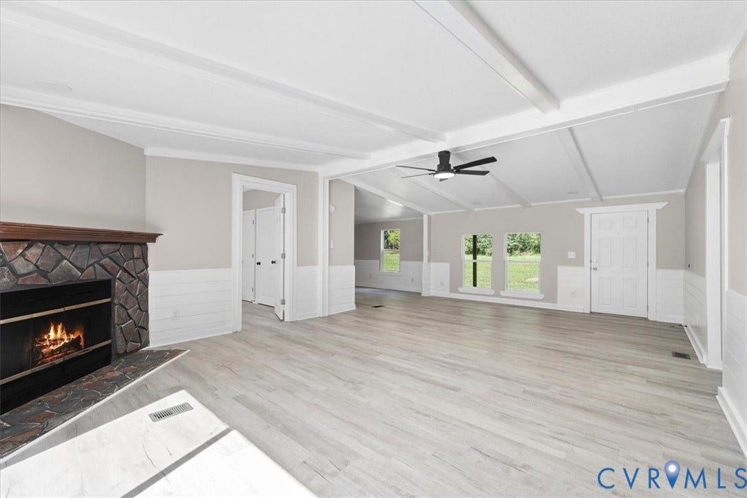 115 Mount Airy Lane, Cumberland, VA 23040 Vaulted ceiling with exposed beams, wood-finish flooring, stone fireplace with hearth, white wainscoting, and a ceiling fan
