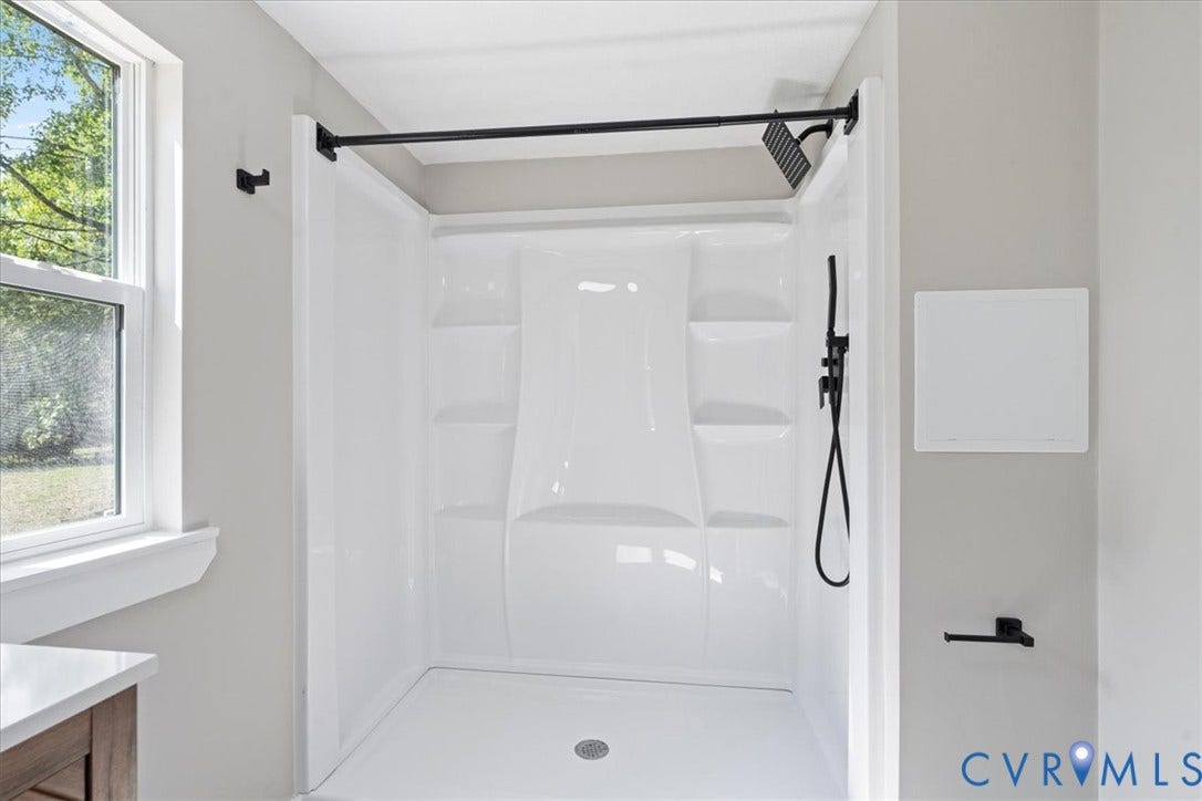 115 Mount Airy Lane, Cumberland, VA 23040 White shower enclosure with integrated shelving, matte black shower fixtures, and a shower curtain rod