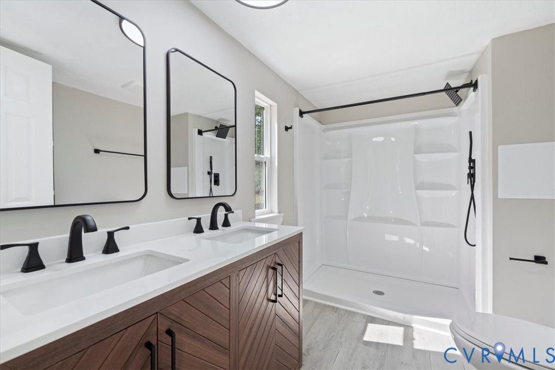 115 Mount Airy Lane, Cumberland, VA 23040 Primary bathroom featuring dual vanities with white quartz countertops, wood-finish cabinetry with integrated hardware, matte black fixtures, and framed mirrors