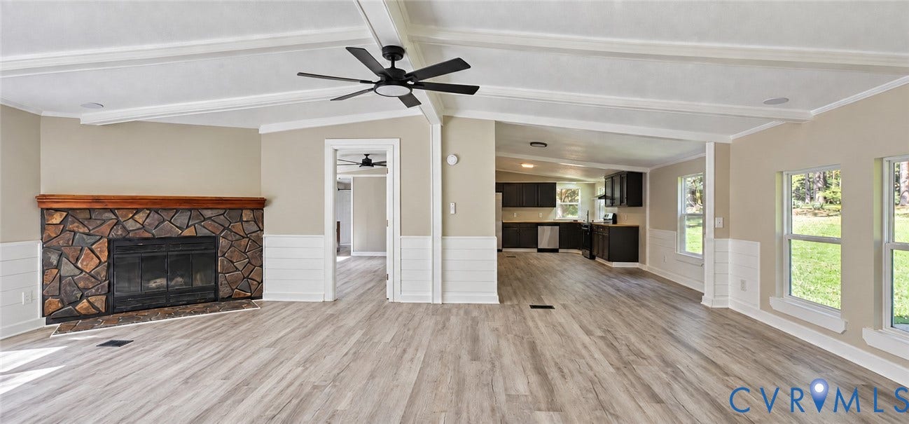115 Mount Airy Lane, Cumberland, VA 23040 Spacious interior featuring wood-finish flooring, a stone fireplace with a wood mantel, vaulted ceilings, and white shiplap wainscoting