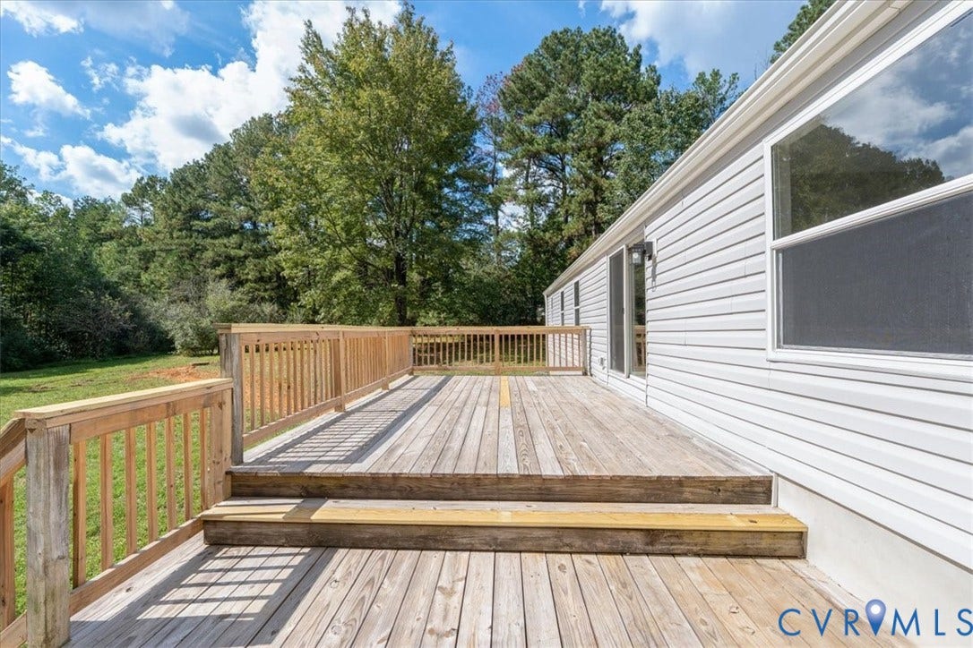 115 Mount Airy Lane, Cumberland, VA 23040 Expansive wood deck with railing and dual steps, featuring white siding and exterior wall lighting