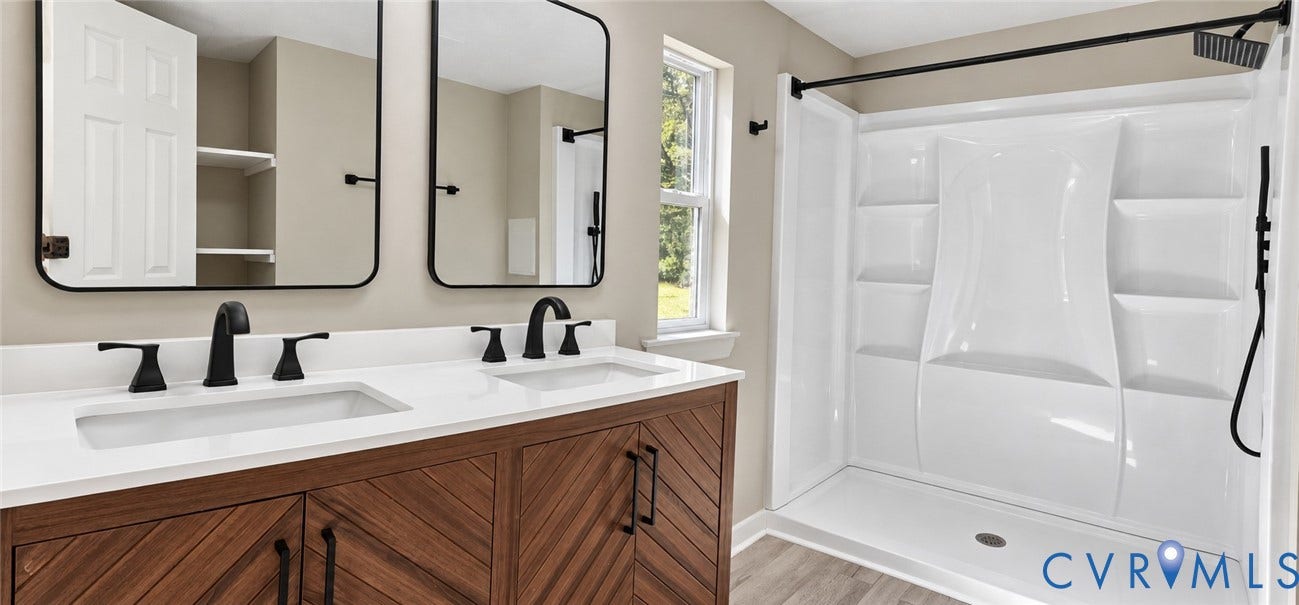 115 Mount Airy Lane, Cumberland, VA 23040 Double vanity with a white countertop and matte black faucets, wood-finish cabinetry, and framed mirrors