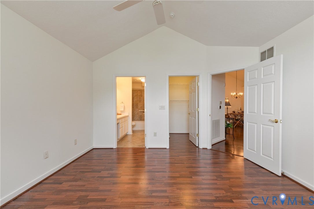 Vaulted ceiling with a ceiling fan, wood finished flooring, white paneled doors, and an accessible closet