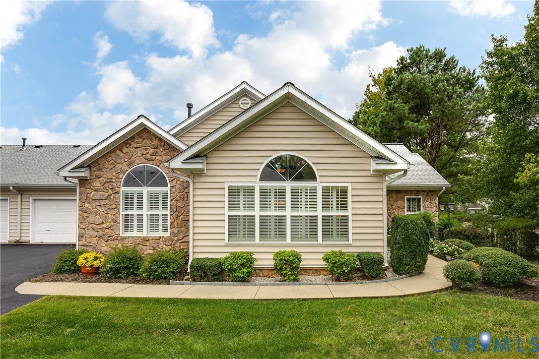 Stone and siding exterior with arched windows, prominent gables, and an attached garage