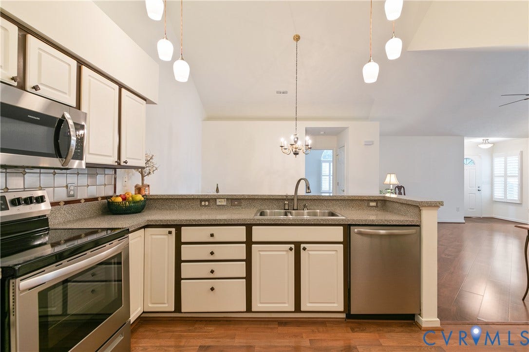 Kitchen featuring stainless steel appliances, dual basin sink, light-toned cabinetry, and wood-finish flooring