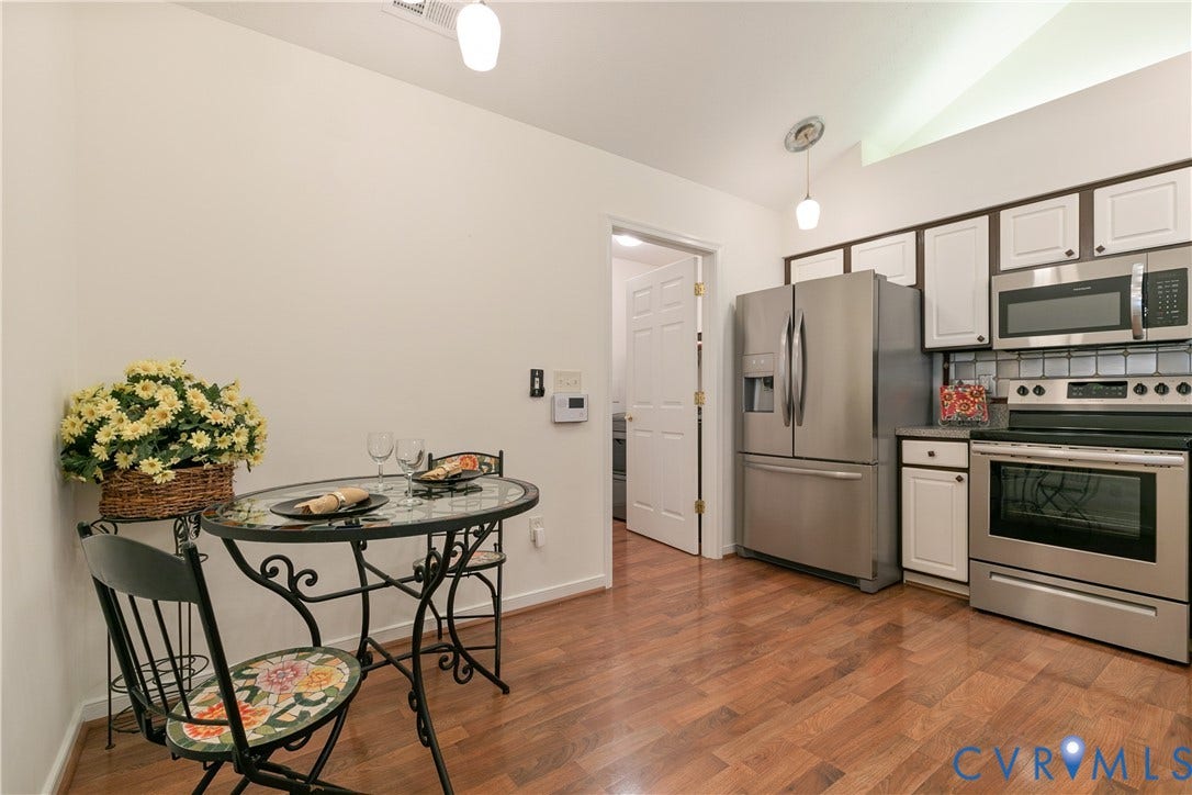 Kitchen featuring stainless steel appliances, wood-finish flooring, white cabinetry, and a tile backsplash