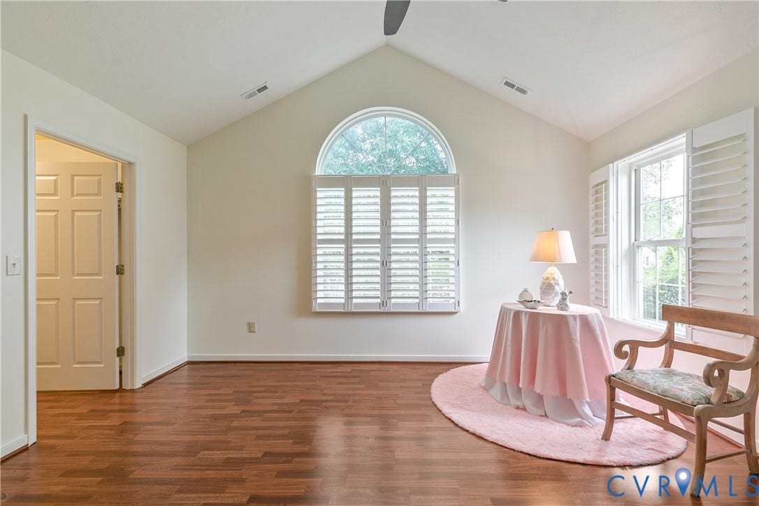 Vaulted ceiling with an arched window and white plantation shutters.