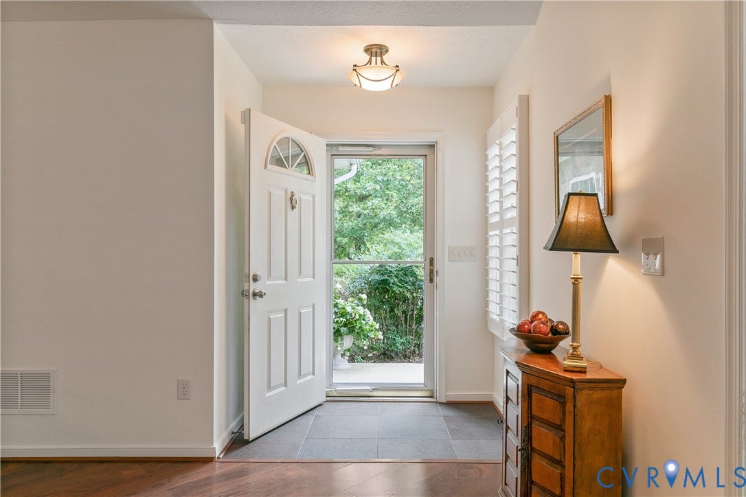 Entryway featuring a paneled door with an arched transom, a ceiling-mounted light fixture, wood-finish flooring, and a tiled landing