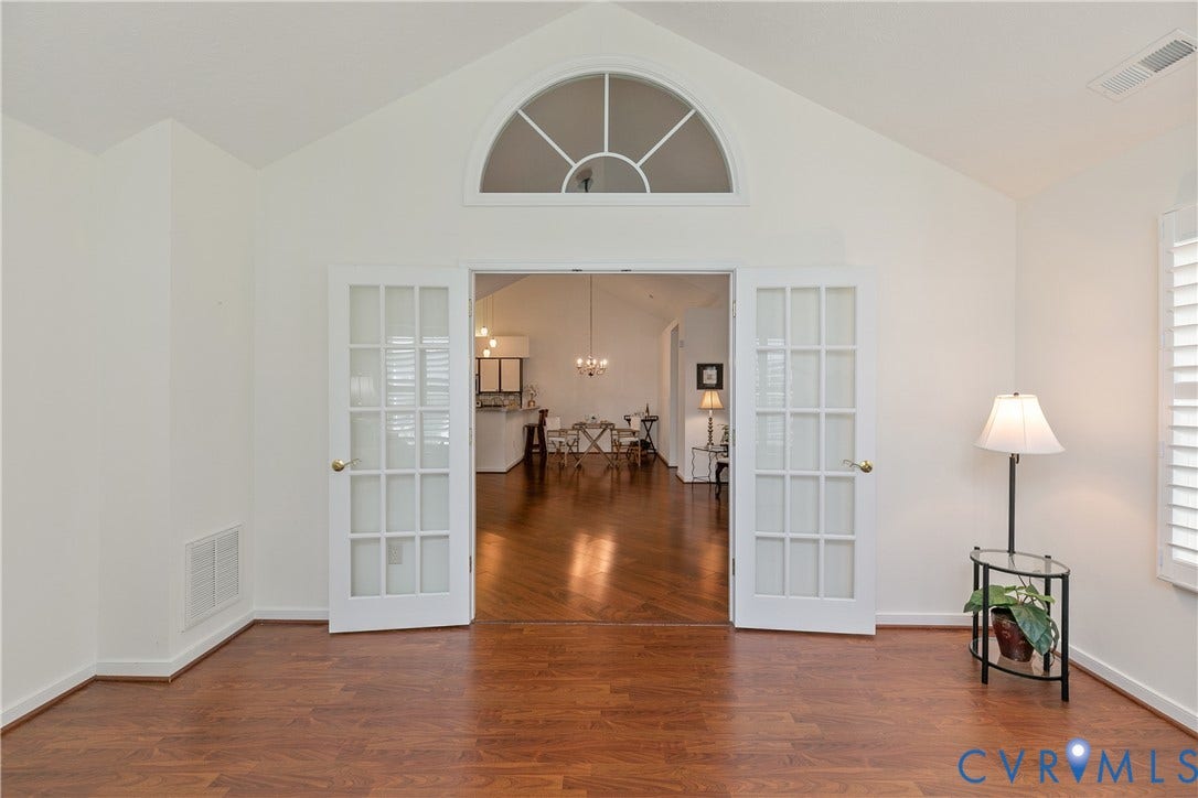 Vaulted ceiling with an arched transom window, French doors, wood-finish flooring, and white plantation shutters