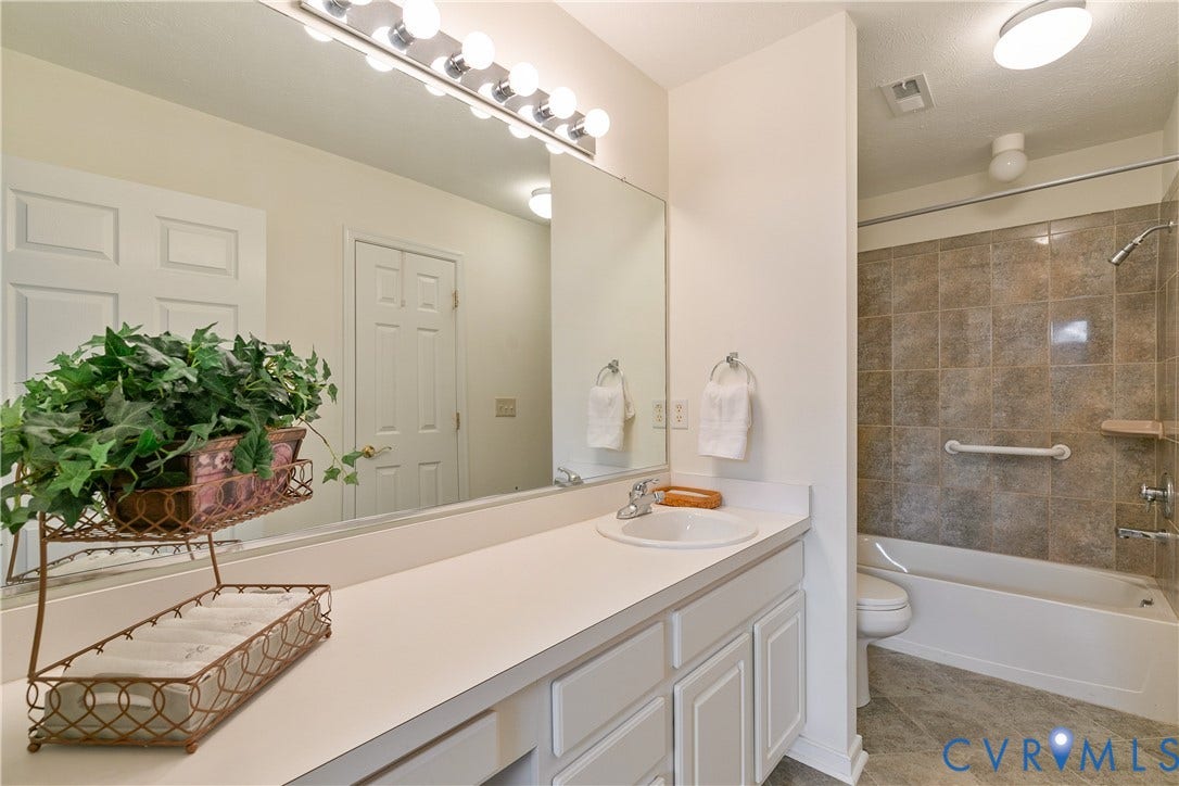 Spacious vanity with an integrated sink, broad wall mirror, and overhead strip lighting