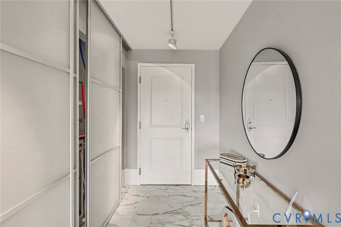 1101 Haxall Point, #U512 U510, Richmond, VA 23219 Hallway featuring marble-finish flooring, a white paneled door, and a built-in closet with sliding frosted doors