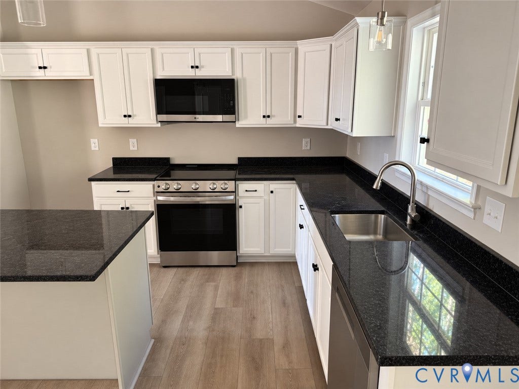 7735 Jefferson Highway, Cedar Hill Park, Mineral, VA 23117 White shaker cabinetry with dark hardware, dark countertops, stainless steel range and microwave, stainless steel sink, and wood-finish flooring