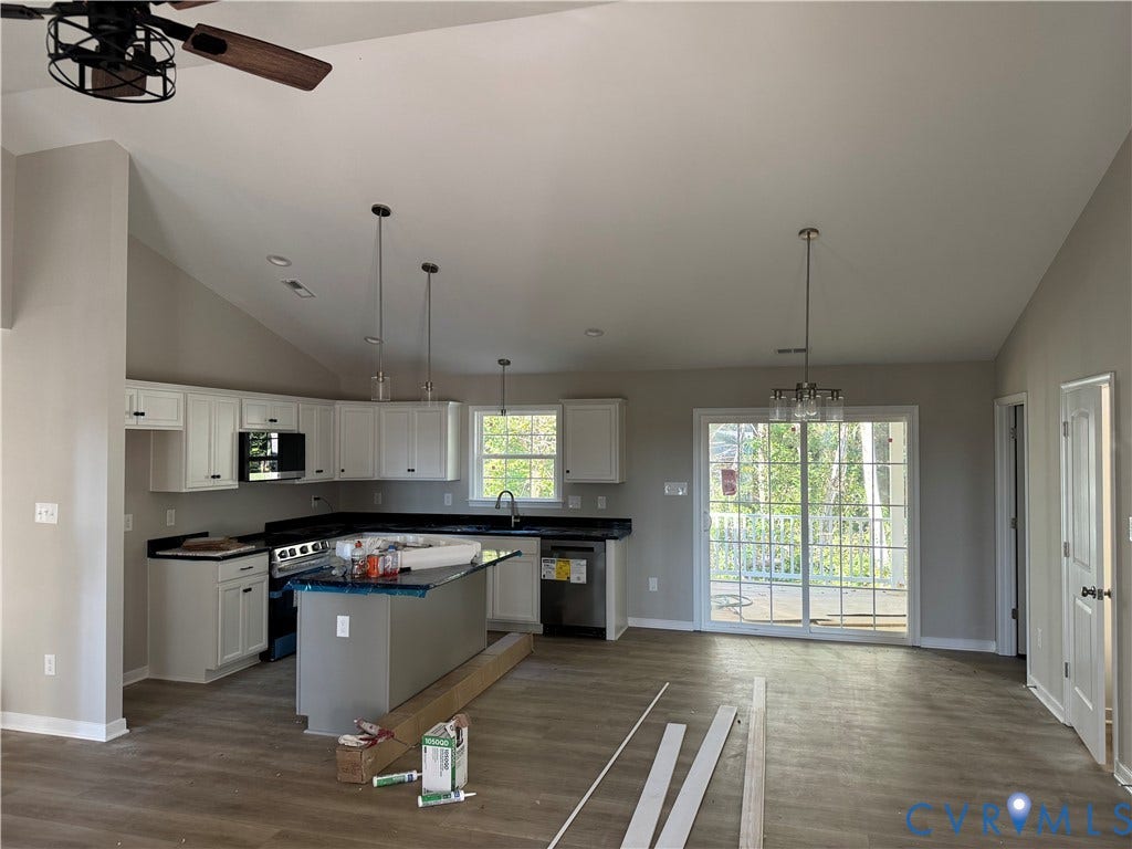 7735 Jefferson Highway, Cedar Hill Park, Mineral, VA 23117 Vaulted ceiling with a ceiling fan, white cabinetry with dark countertops, kitchen island, stainless steel appliances, and wood-finish flooring