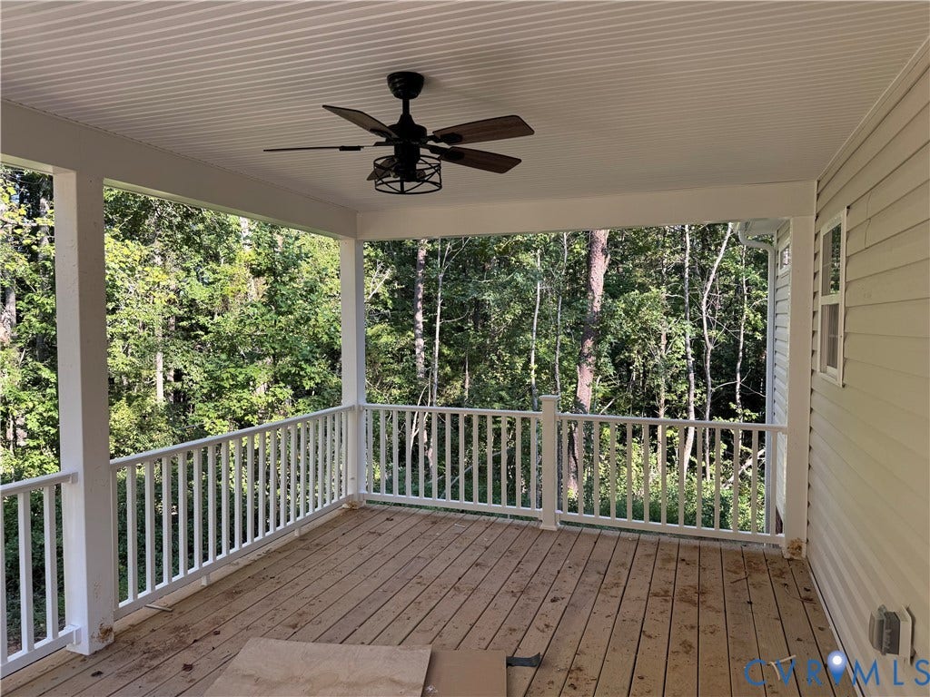 7735 Jefferson Highway, Cedar Hill Park, Mineral, VA 23117 Covered outdoor deck featuring a ceiling fan, plank flooring, white railing, and a wooded backdrop