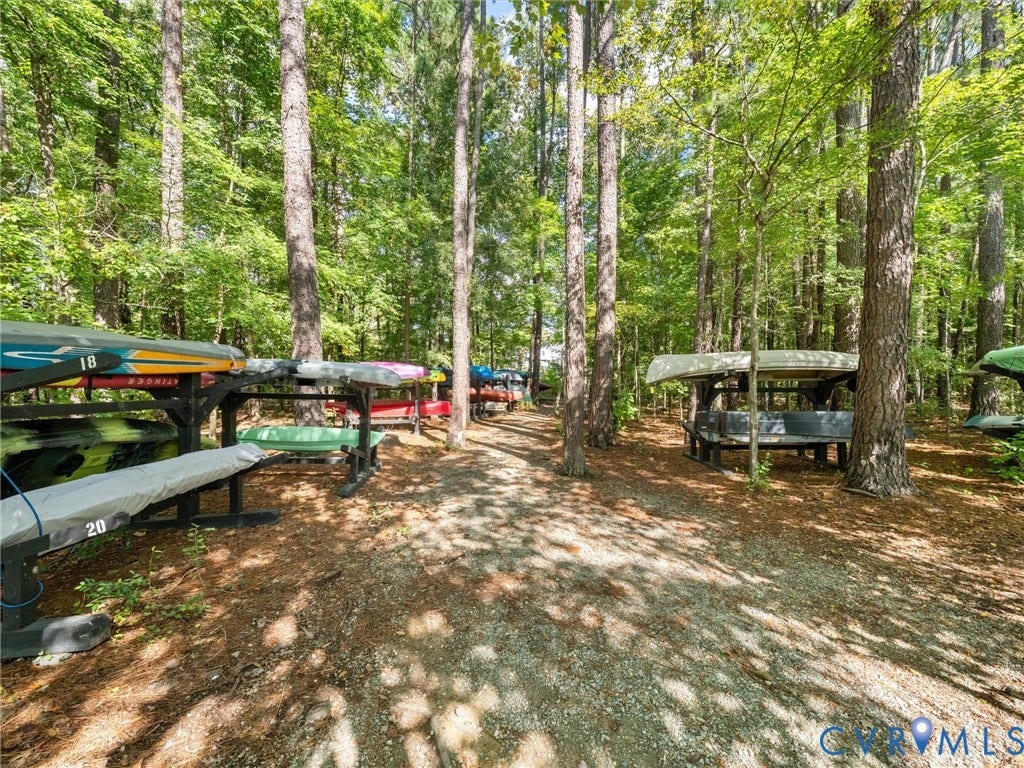 Wooded property featuring a gravel path and multiple boat storage racks