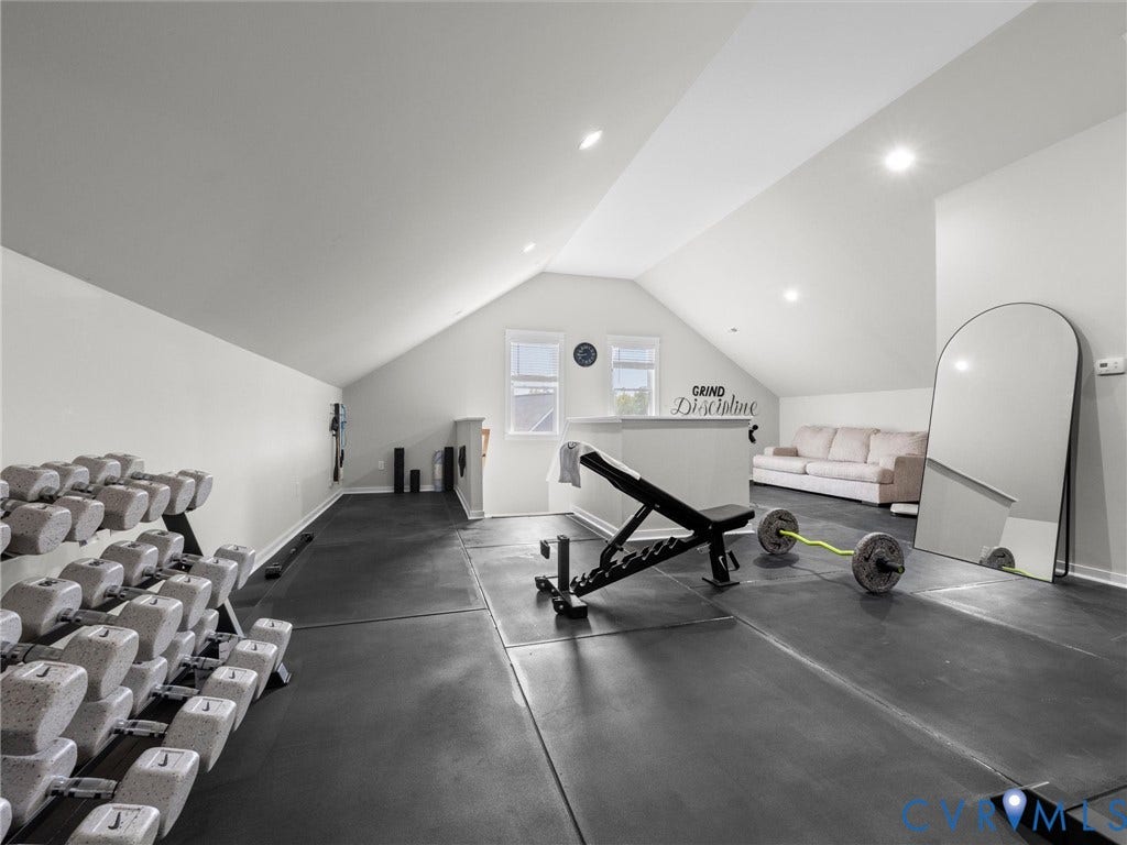 Vaulted ceiling with recessed lighting, two windows, and black rubber flooring