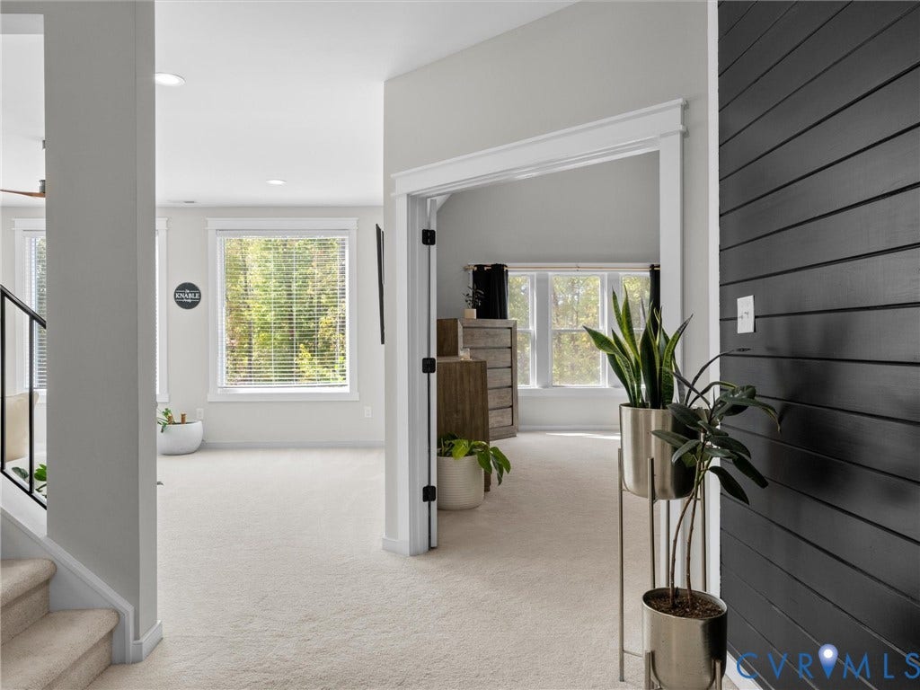 Black shiplap accent wall, light-toned carpeting, ample natural light from multiple windows, recessed lighting, and a white trim package