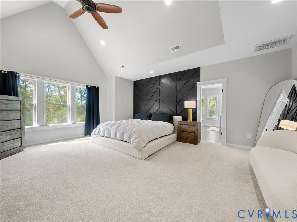 Vaulted ceiling with a ceiling fan, accent wall with geometric paneling, recessed lighting, and large windows with privacy drapery